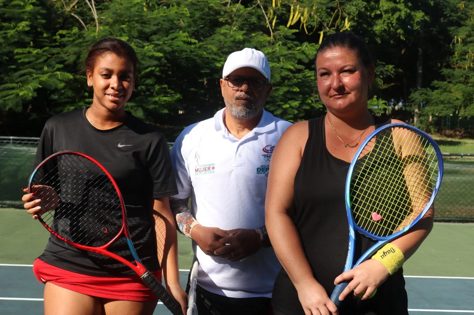 Tres personas con raqueta en la cancha.